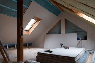Attic space with pile of drywalls at center of floor and partial finished walls