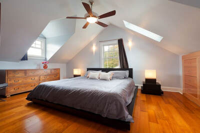 Converted attic bedroom with ceiling fan and king size bed