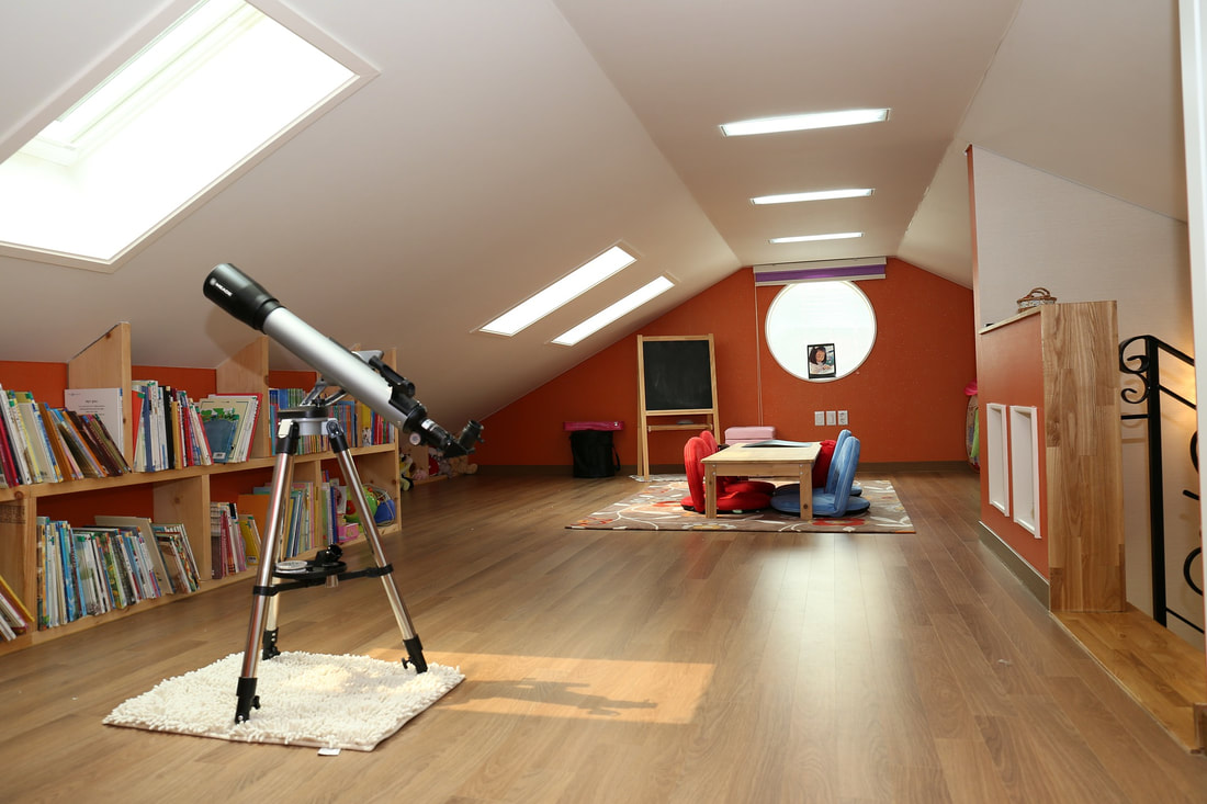 Converted attic space with telescope, children's table, and bookshelves