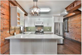 Remodel kitchen with 2 side brick walls, white cabinets, white island, and green backsplash